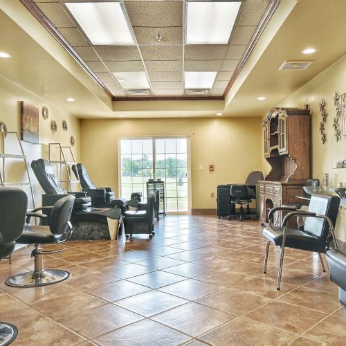 The image shows a salon interior with chairs, mirrors, and workstations, featuring a spacious and well-lit environment.