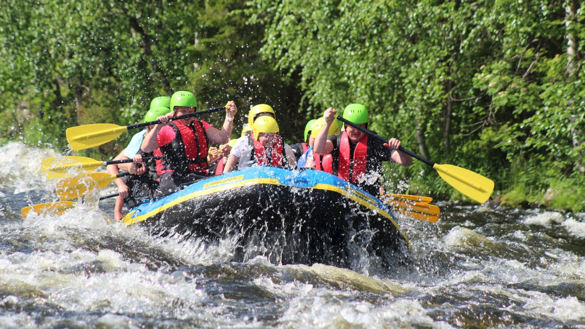 People in helmets and life jackets are white-water rafting in a river, surrounded by lush greenery.