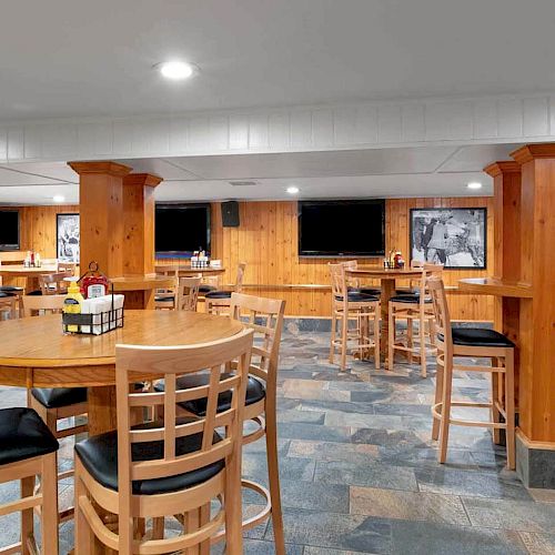 A cozy dining area with wooden furniture, tables, and chairs arranged neatly, featuring wall art and a warm, inviting atmosphere.