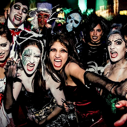 The image shows a group of people in Halloween costumes and makeup, posing and making expressive faces.