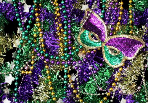 The image features colorful beads and a decorative mask in shades of purple, green, and gold, likely associated with a festive or carnival event.