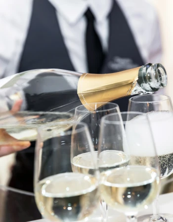 A person pours champagne into glasses at an event, creating a festive atmosphere.